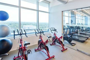 A gym with exercise bikes and a view of the city at Two Twelve Clayton Apartments, Clayton, MO